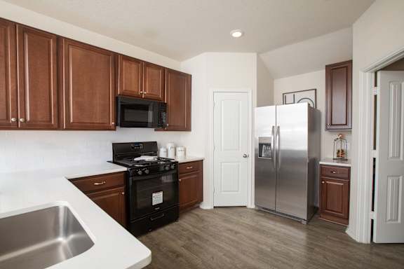 A kitchen with brown cabinets and a stainless steel refrigerator at Caney Mills, Conroe, TX 77303