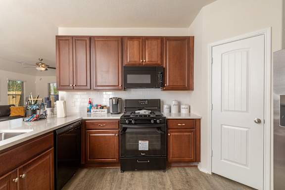 A kitchen with brown cabinets and a black stove at The Village at Caney Mills, Conroe, TX