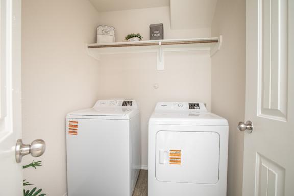 Two white washing machines in a small laundry room at Caney Mills, Conroe, 77303