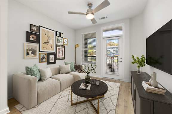A living room with a beige couch, a coffee table, and a television.