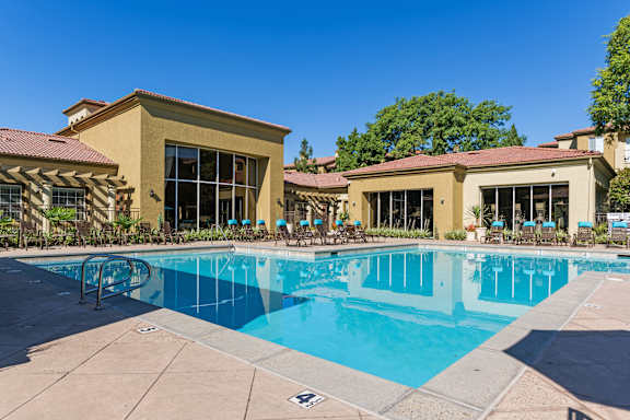 A large swimming pool in front of a building with a red tile roof.