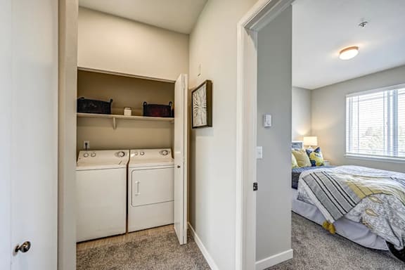 A bedroom with a washer and dryer in the closet.