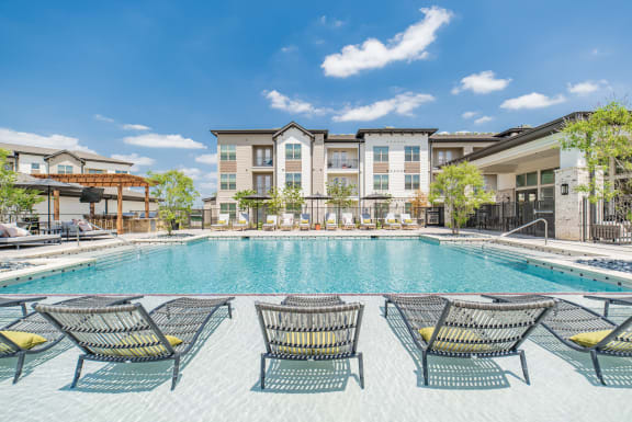 a swimming pool with lounge chairs and buildings in the background