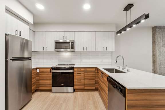 A modern kitchen with stainless steel appliances and wooden cabinets at Ion Town Center, Shoreline, WA.
