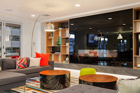 A modern living room with a grey couch, a wooden coffee table, and a large window.