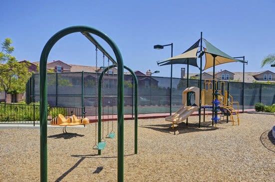 A playground with a swing set and a slide at RiverEdge Terrace* Apartments, San Diego, CA
