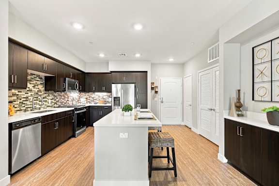 A kitchen with a white island and wooden floors.