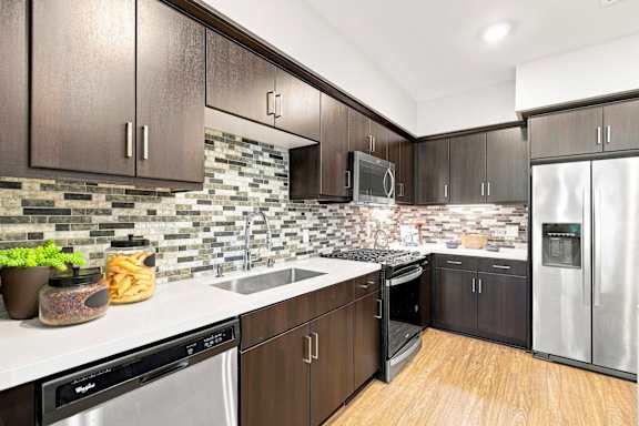 A kitchen with dark brown cabinets and a backsplash of stone tiles.