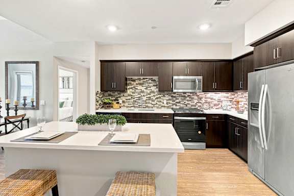 A modern kitchen with a white island and stainless steel appliances.