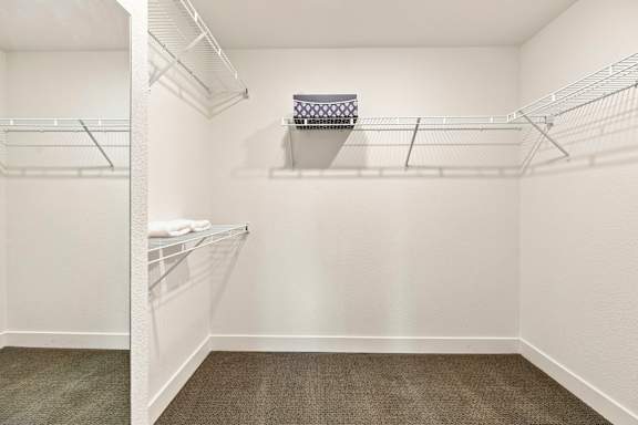 A white walk-in closet with shelves and a basket on top.