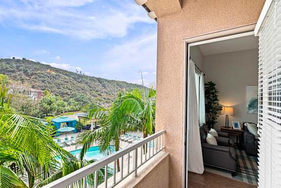 A balcony view of a pool with a mountain in the background.