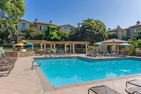 A large swimming pool surrounded by lounge chairs and umbrellas.