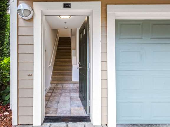 A white door is open to a hallway with a staircase.
