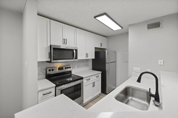 a kitchen with white cabinets and stainless steel appliances and a sink