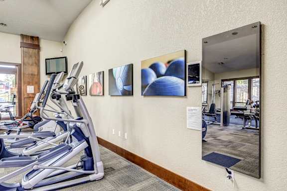A gym with treadmills and mirrors on the wall.
