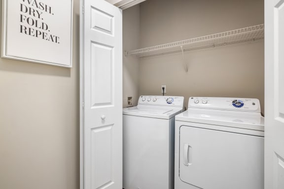 an empty laundry room with two white washers and dryers and a white door