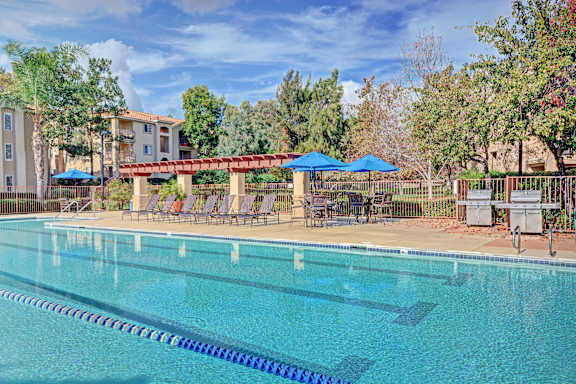 a swimming pool with chairs and umbrellas at a resort pool