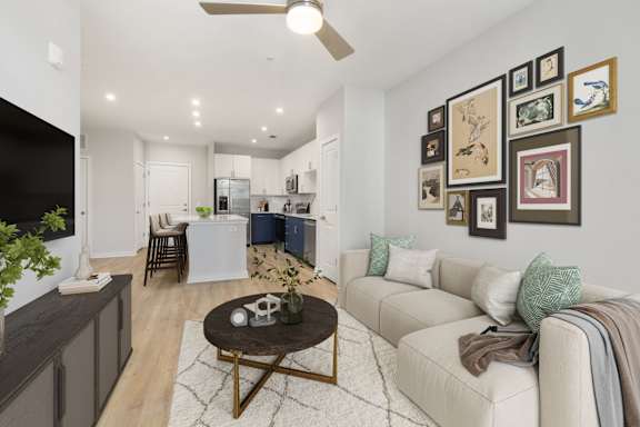 A living room with a white couch, a coffee table, and a wall of framed pictures.