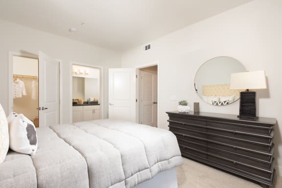 a bedroom with a large bed and a dresser with a mirror