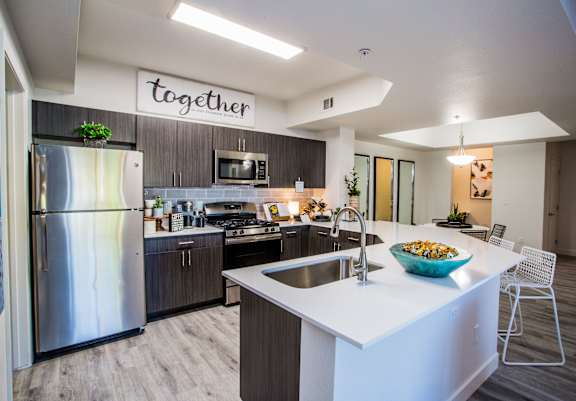 A modern kitchen with a large island and a refrigerator with a glass door.