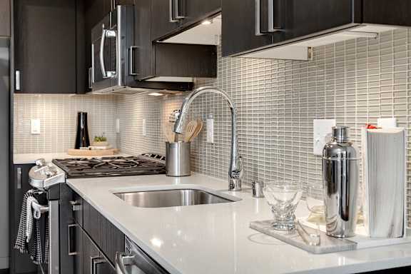 A modern kitchen with a stainless steel sink and black cabinets.