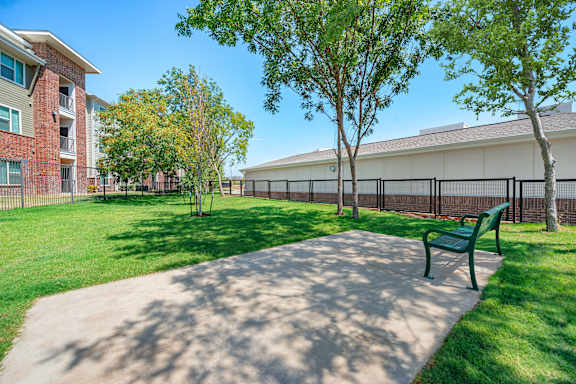 A green bench sits in the middle of a concrete walkway.