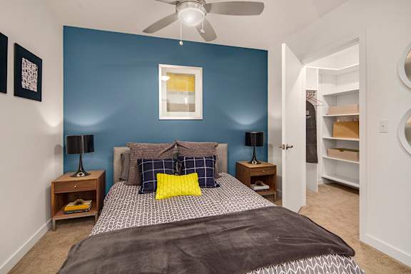 A bedroom with a bed, two lamps, and a ceiling fan.