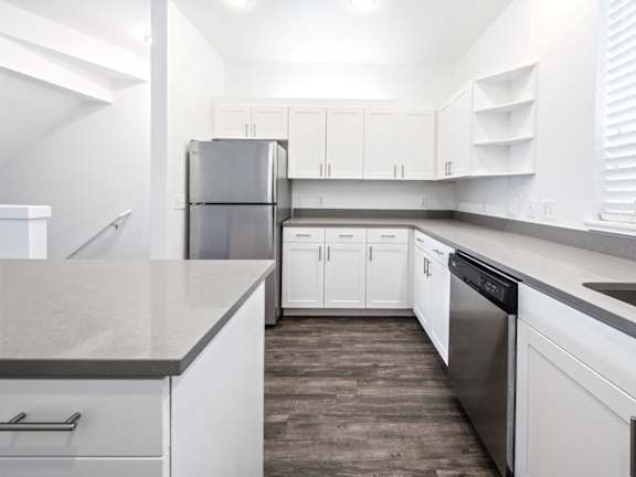 A kitchen with white cabinets and a stainless steel refrigerator.