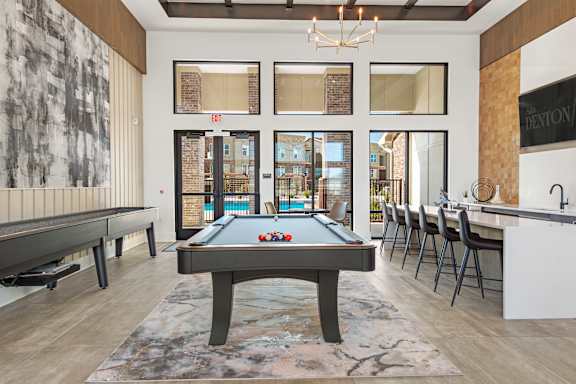 A billiard table is in the middle of a room with a pool table on the left.