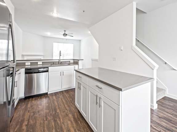 A kitchen with white cabinets and a wooden floor.