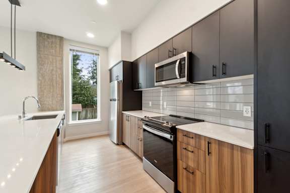 A modern kitchen with wooden cabinets and black appliances. at Ion Town Center, WA