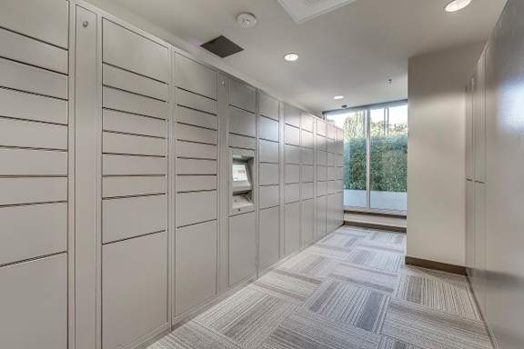 A hallway with a row of lockers on the left and a window on the right.