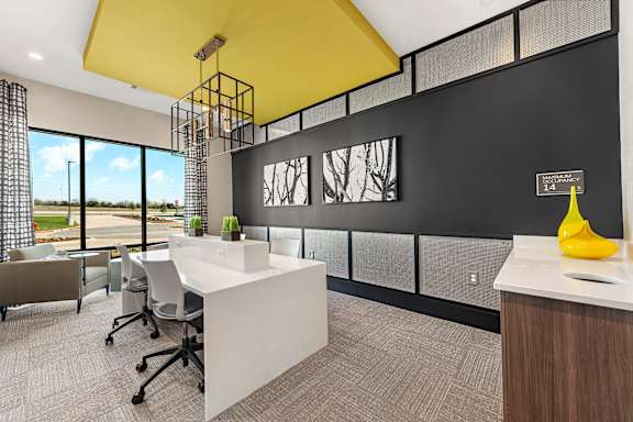 A modern office with a yellow ceiling and a long window overlooking a field.