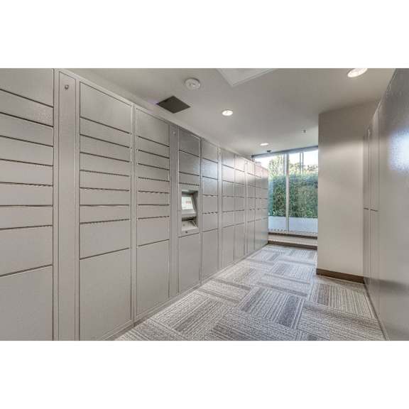 A hallway with a row of lockers on the left and a carpeted floor.