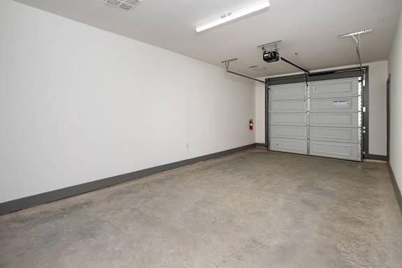 A large empty room with a white wall and a closed white door at the end.
