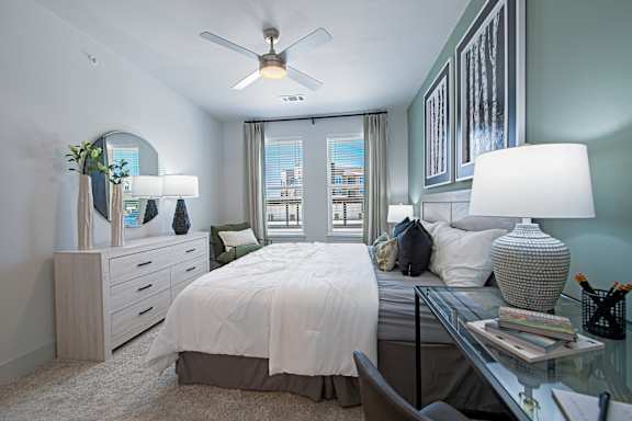 A bedroom with a bed, nightstand, and a ceiling fan.