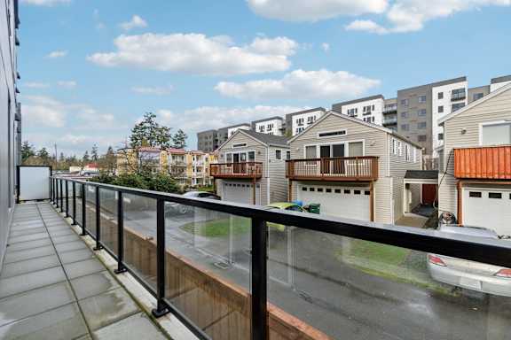 A balcony with a black railing overlooks a residential area with houses and cars at Ion Town Center, WA.