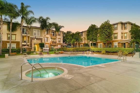 A swimming pool surrounded by palm trees and apartment buildings.
