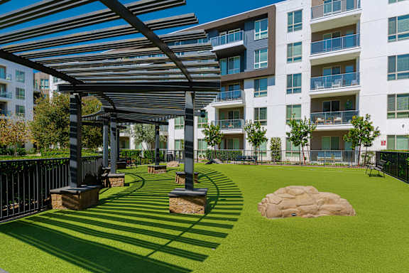 A large grassy area with a shaded walkway in front of apartment buildings.