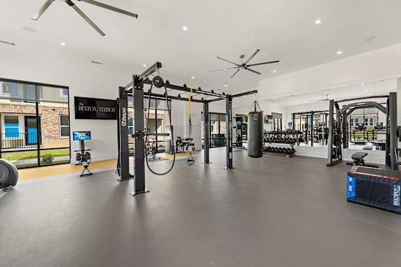 A gym with a variety of equipment including a weight bench, a rowing machine, and a treadmill.