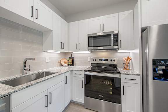 A modern kitchen with white cabinets and stainless steel appliances.