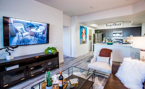 A living room with a television on the wall and a couch with a white pillow.