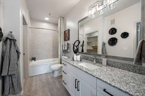 A bathroom with a white toilet, a white bathtub, a sink, and a large mirror.