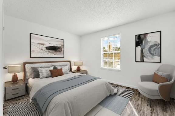 A bedroom with a large bed, a chair, and two framed pictures on the wall.