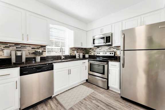 A kitchen with white cabinets and stainless steel appliances.