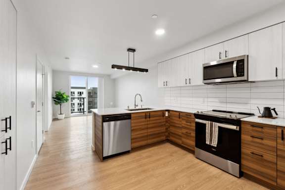 A modern kitchen with wooden cabinets and stainless steel appliances. at Ion Town Center, Shoreline, WA