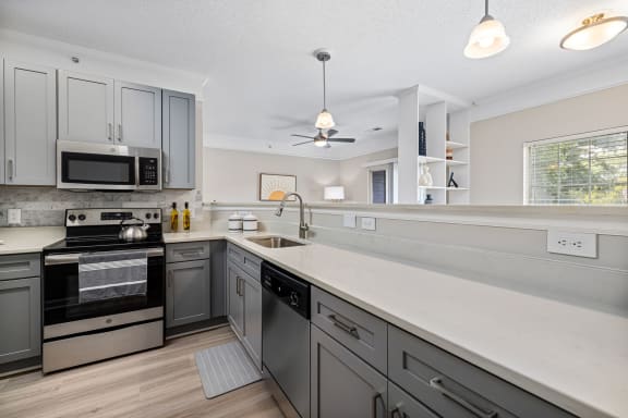 a large kitchen with white counter tops and stainless steel appliances
