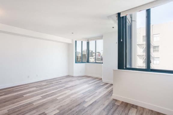 an empty room with a large window and hardwood floors