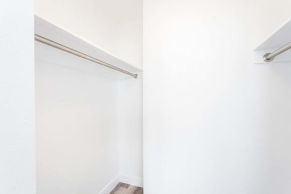 a walk in closet in a bedroom with white walls