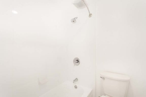 a white bathroom with a white toilet and a white bathtub